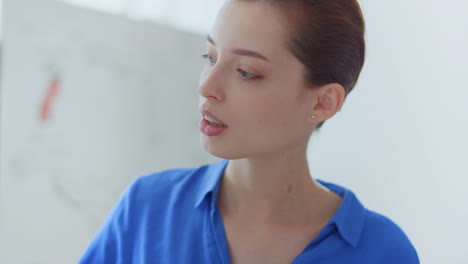 Woman-face-looking-white-board-indoors.-Business-coach-hand-pointing-flip-chart