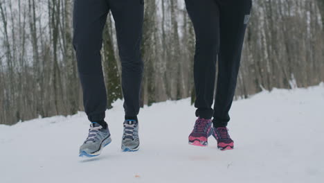 close-up of the feet of two runners in sneakers running in the winter in the park. the married couple goes in for sports.