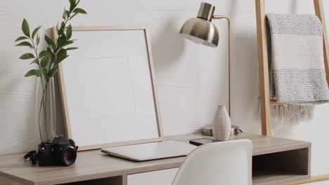 white frame with copy space on white background with plant on desk against white wall