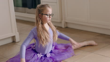 happy ballerina girl dancing in kitchen having fun practicing ballet dance moves wearing purple tutu at home