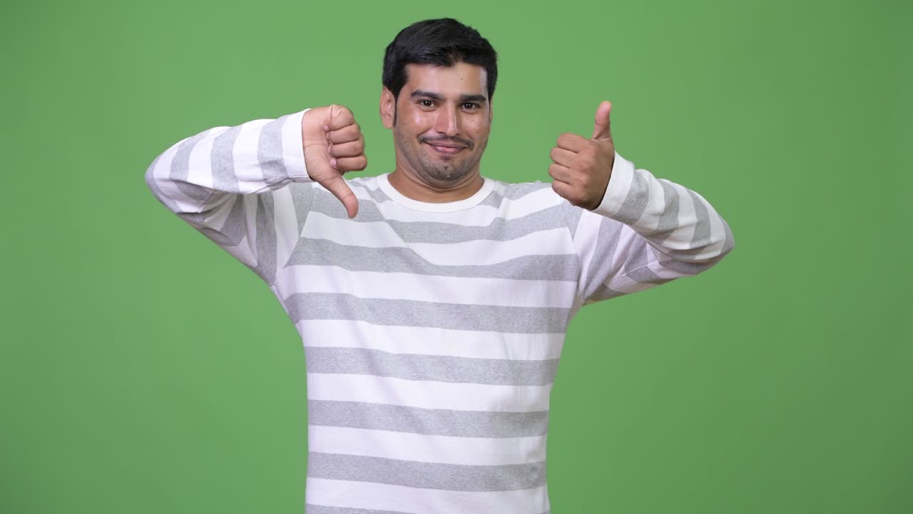 Young handsome Persian man choosing between thumbs up and thumbs down