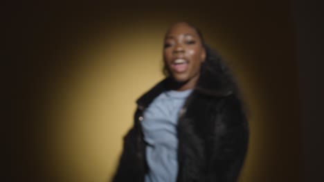 studio portrait shot of young woman dancing in spotlight against yellow background