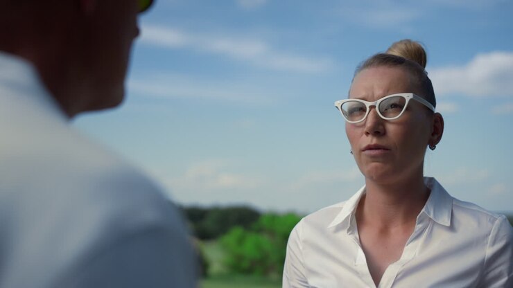 Donna d'affari parla all'aperto al golf club. Signora seria che chiacchiera sul campo da golf.