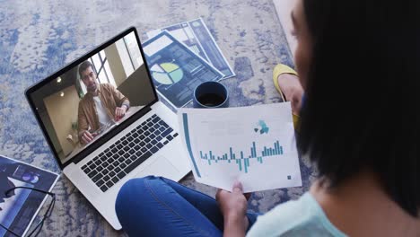 African-american-woman-holding-a-document-having-a-video-call-on-laptop-at-home