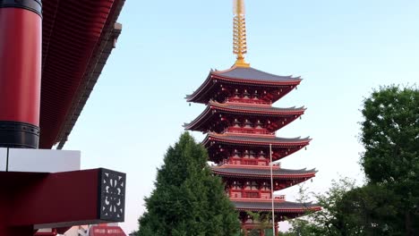 Pagoda-with-red-and-gold-details-amidst-greenery-at-dusk-in-Japan