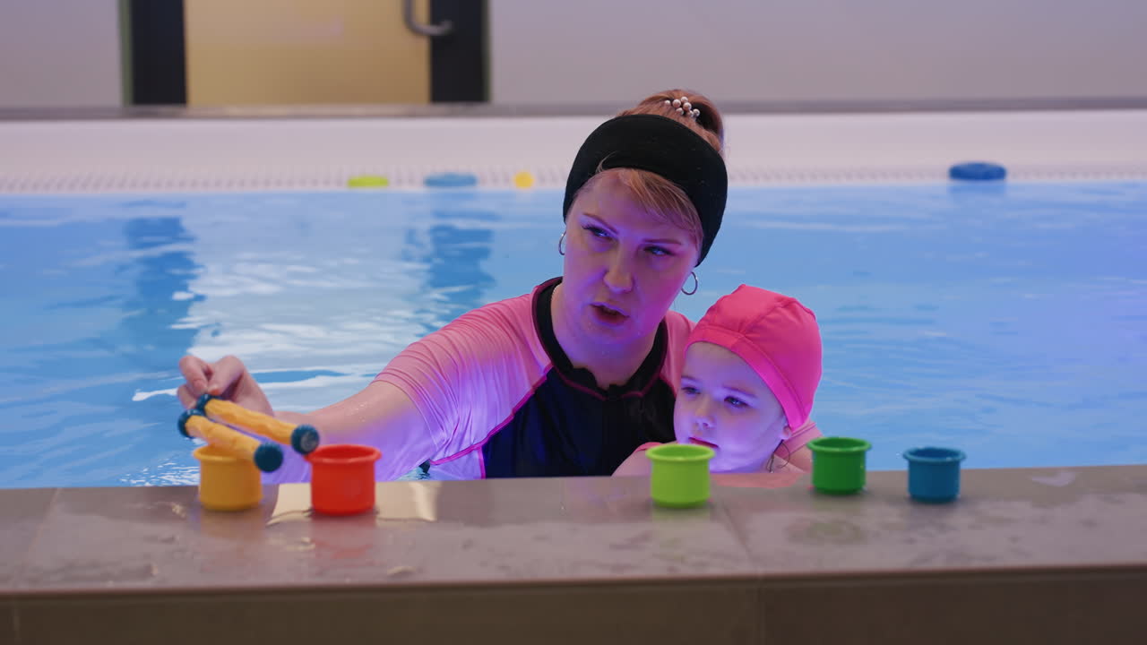 Un profesor clasifica palitos de colores en vasos a juego, colocando cada palito en el vaso del mismo color, momento instructivo tranquilo, vista cercana de las manos que demuestran el reconocimiento del color, enfoque en el aprendizaje temprano.