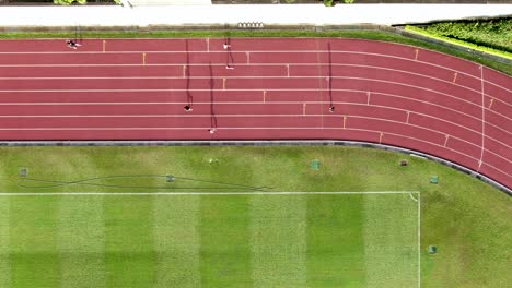 People-during-Early-morning-Jogging-on-a-racetrack-with-long-starched-silhouettes,-Aerial-view