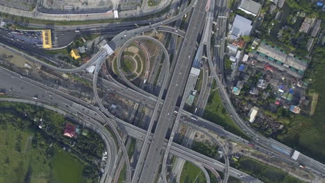 Vista-Aérea-Del-Cruce-De-Carreteras-Con-Tráfico-Urbano-Intenso-Acelerando-En-La-Carretera