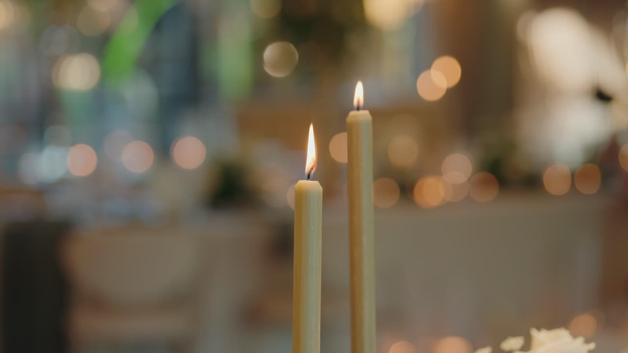 two lit candles glow softly in elegant reception bokeh backdrop