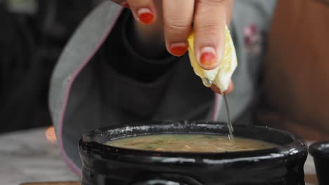 woman adding lemon juice to soup