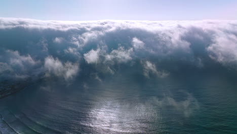thick white fog spreading to the coastline from water. amazing cloudscape of haze on sunny summer day. aerial view.