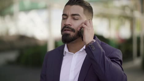 Un-Hombre-De-Negocios-Serio-Hablando-Por-Teléfono-Celular-Al-Aire-Libre