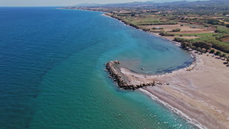 aerial view of a serene beach with rocky jetty along the coastline