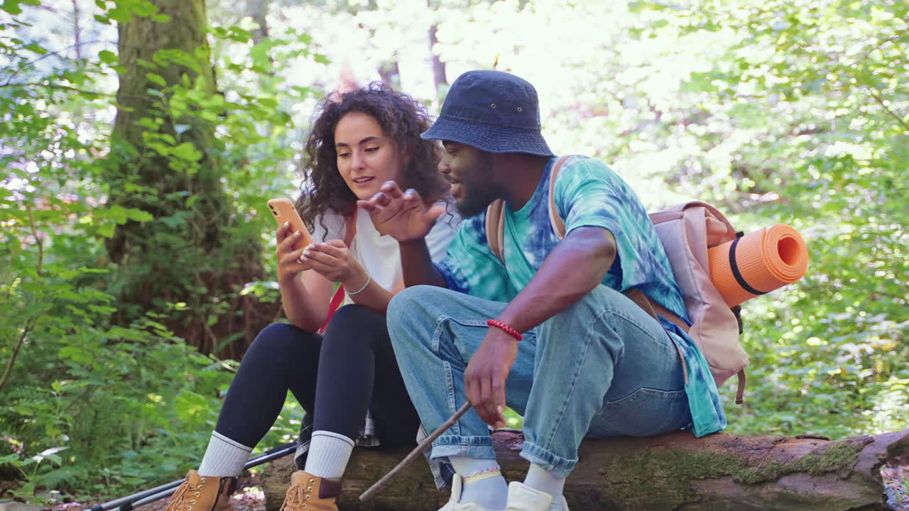 pareja de senderismo en el bosque usando un teléfono inteligente
