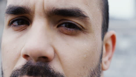 close-up view of the sweaty face of the male boxer during a training outdoors an abandoned factory on a cloudy morning