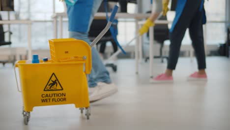 janitor taking detergent spray from yellow cart to clean office windows