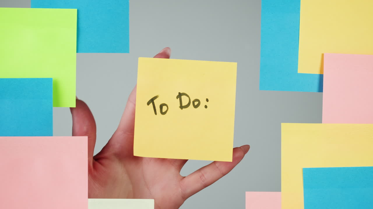 Hand Placing 'To Do' Sticky Note on a Gray Background