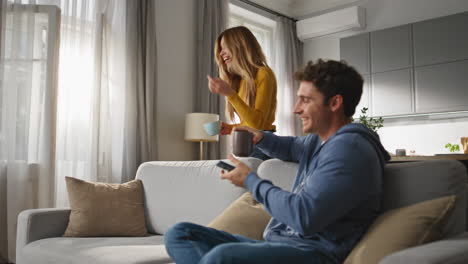 smiling man browsing smartphone chilling sofa closeup. happy wife bringing tea