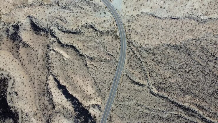 Lonely vehicle driving on desert road in California, aerial top down shot
