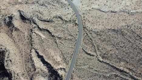 lonely vehicle driving on desert road in california, aerial top down shot