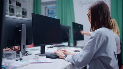 mujer joven trabajando en una computadora en un entorno de oficina