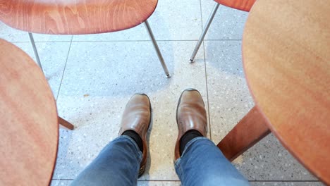 a person's feet sitting between two wooden chairs