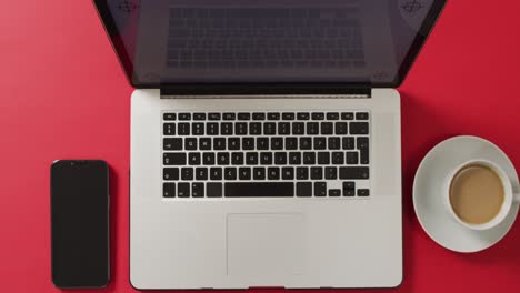 vista aérea de la computadora portátil con teléfono inteligente y café en el escritorio rojo