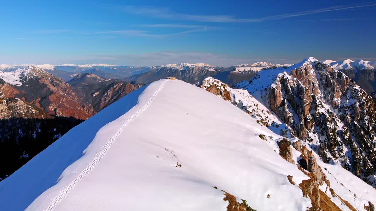 volando alto sobre las montañas más altas, nieve cubriendo la cresta, un camino en la montaña