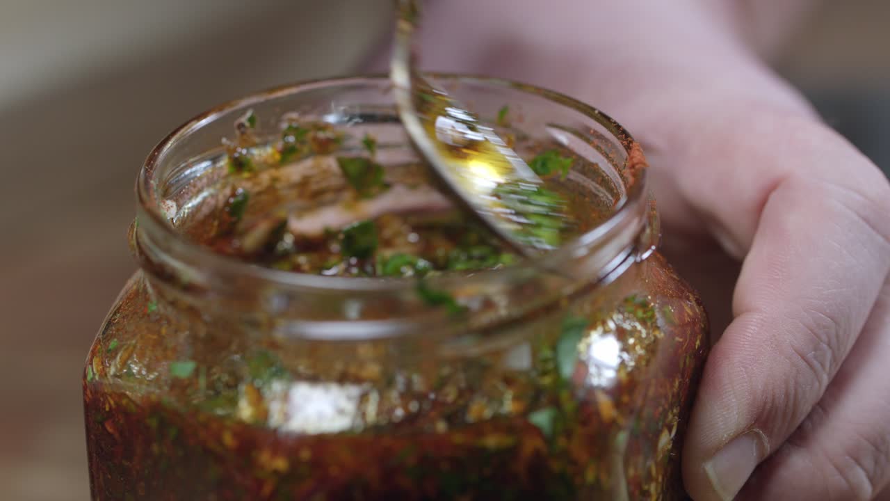 agitando la salsa de chimichurri en un frasco