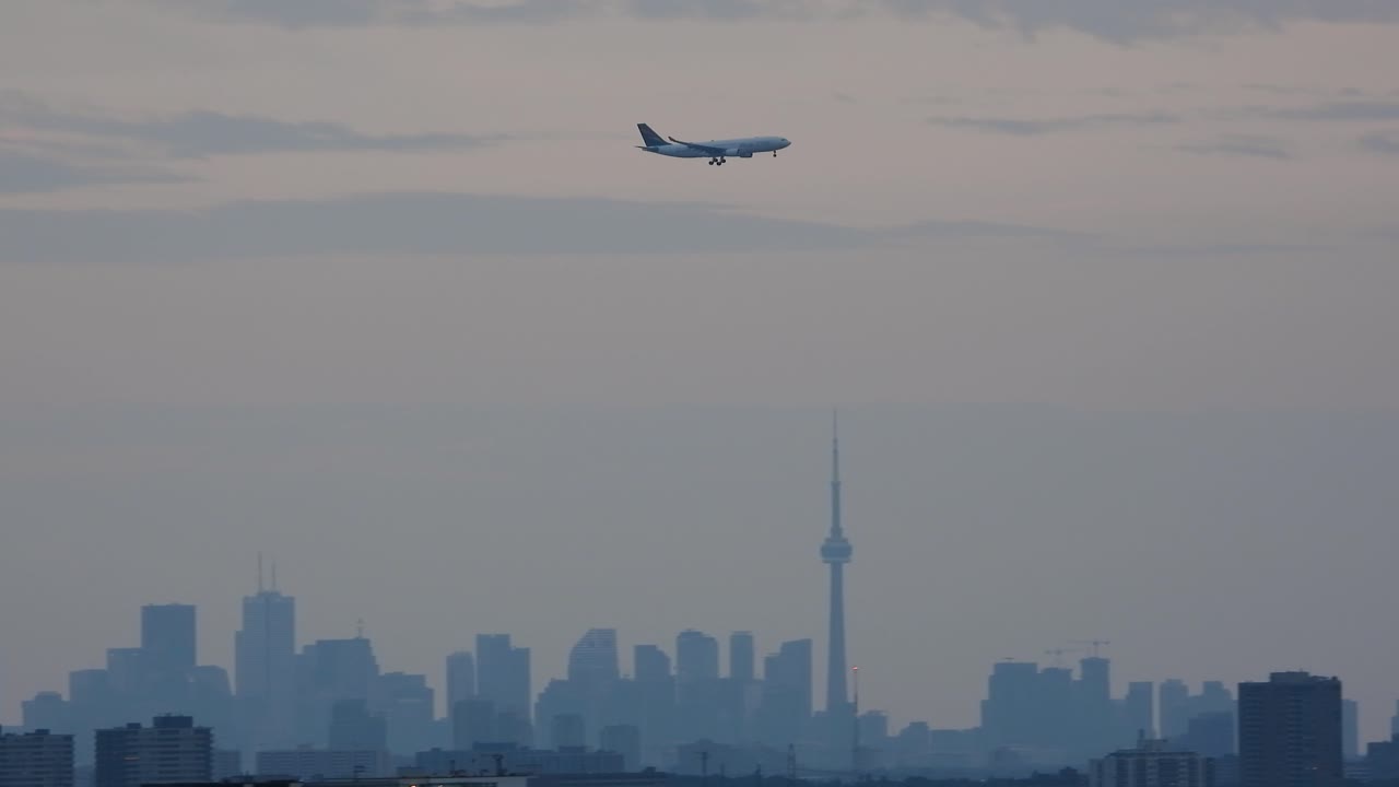 토론토 스카이라인의 실루 위를 날아다니는 상업용 항공기