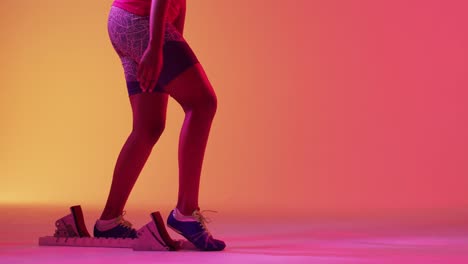 video of focused african american female runner preparing for start on neon orange lightning