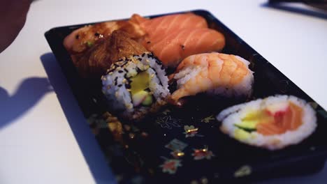macro de primer plano: palillos para comer agarrar sushi de salmón nigiri de un plato adornado