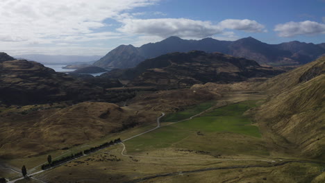 Parapente-En-Wanaka,-Nueva-Zelanda-A-Través-De-Las-Montañas-Y-Colinas-Con-Vistas-A-Un-Lago-Y-Al-Campo-Al-Fondo