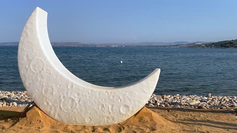 half moon lamp on sandy beach in front of sea for preparation of venue decoration for celebration event