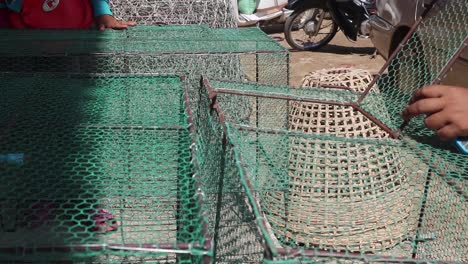 a woman fixing the green plastic net on the cover of a fishing cage - mid shot