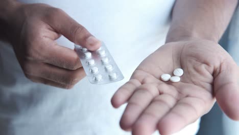 person holding a blister pack of pills and loose pills