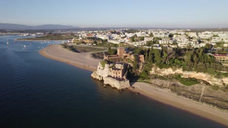 beautiful medieval castle on sand beach in ferragudo, portugal, aerial orbit