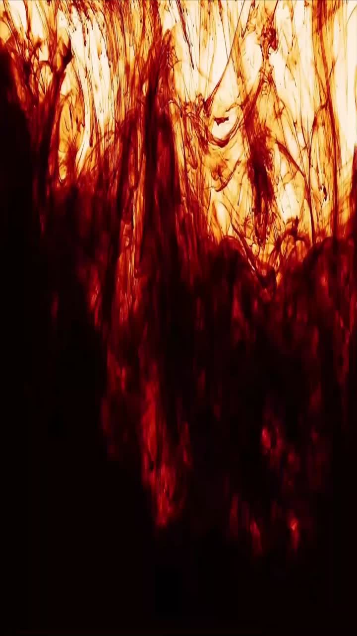 Tinta roja oscura dramática difundiéndose y disolviéndose en agua