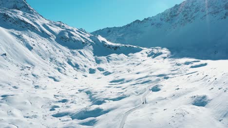 Excelente-Vista-Aérea-De-Un-Coche-Conduciendo-Por-Una-Carretera-Nevada-De-Davos-A-St-Moritz,-Suiza