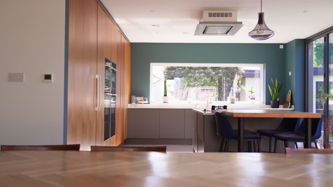 кухня и стойка с встроенными приборами в современном доме с видом на сад