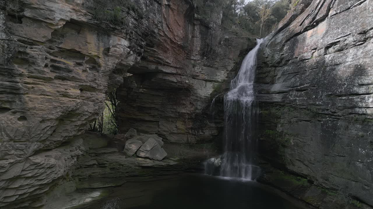 Crystal clear water cascades down la foradada waterfall, creating a mesmerizing spectacle amidst the rugged cliffs and lush vegetation of les guilleries, near barcelona, catalonia, spain