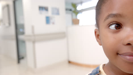 Half-portrait-of-happy-african-american-girl-in-hospital-with-copy-space,-slow-motion