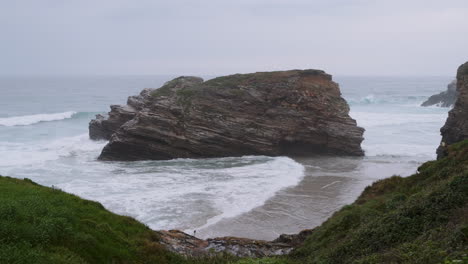 coastal landscape with large sea stack and crashing waves