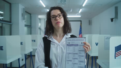 american woman speaks on camera shows paper bulletin calls for voting american woman speaks on camera shows paper bulletin calls for voting national elections day in the united states voting booths at polling station concept of civic duty and patriotism portrait