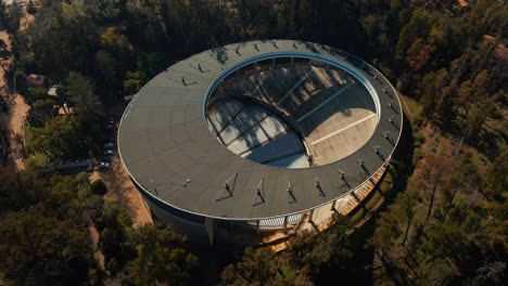 aerial top down dolly out of quinta vergara amphitheater and park surrounded by forest, viña del mar hillside city, chile