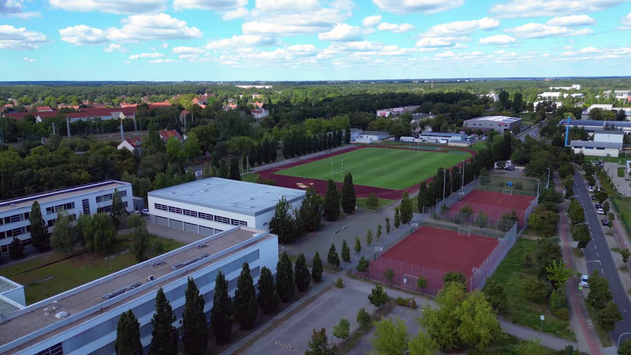 sports facilities at Hennigsdorf high school, including a soccer field, running track and other buildings in residential areas. Great aerial view flight descending drone