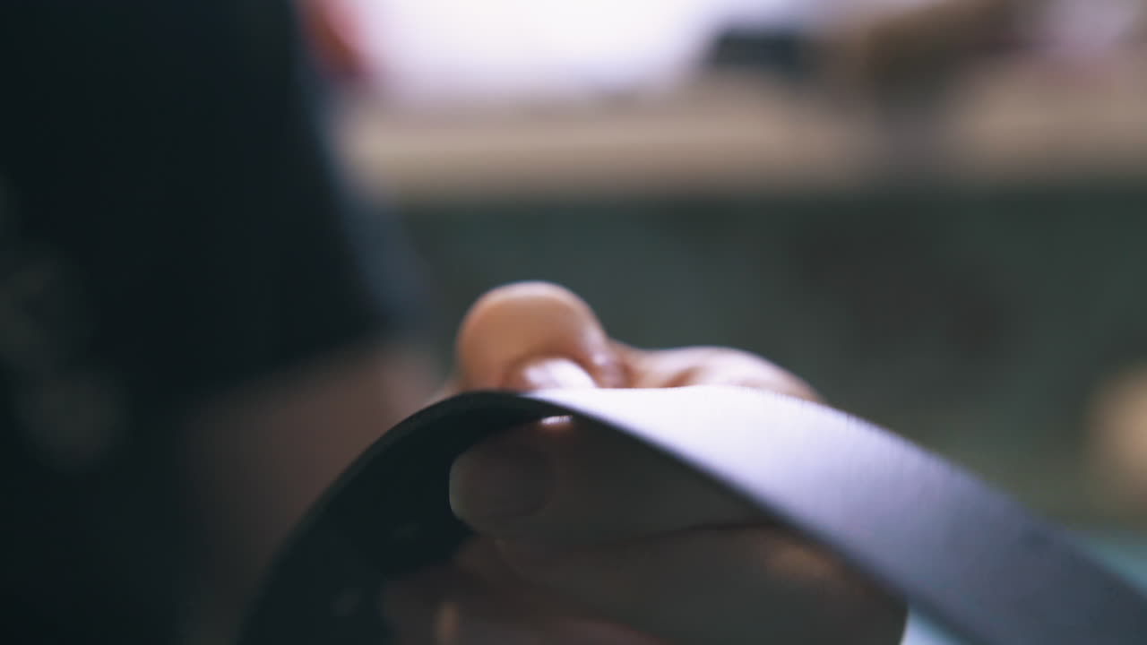 Professional designer makes holes in black leather strip