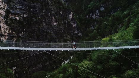 man walks across high suspension bridge between steep cliffs in austria’s gorge