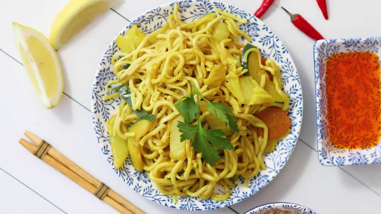 젓가락으로 세라믹 접시에 닭고기와 야채를 곁들인 맛있고 신선한 국수