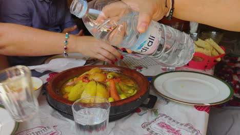 tourists enjoying traditional moroccan cuisine in marrakesh, morocco - close up of uncovering tajine